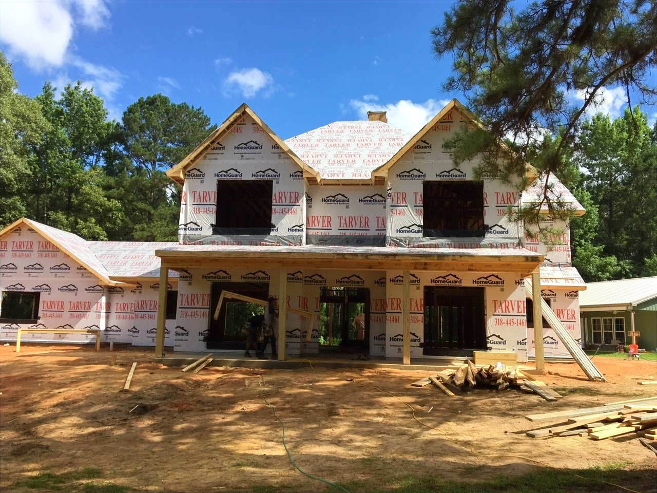 A two-story custom home under construction, framing and roof felt in place