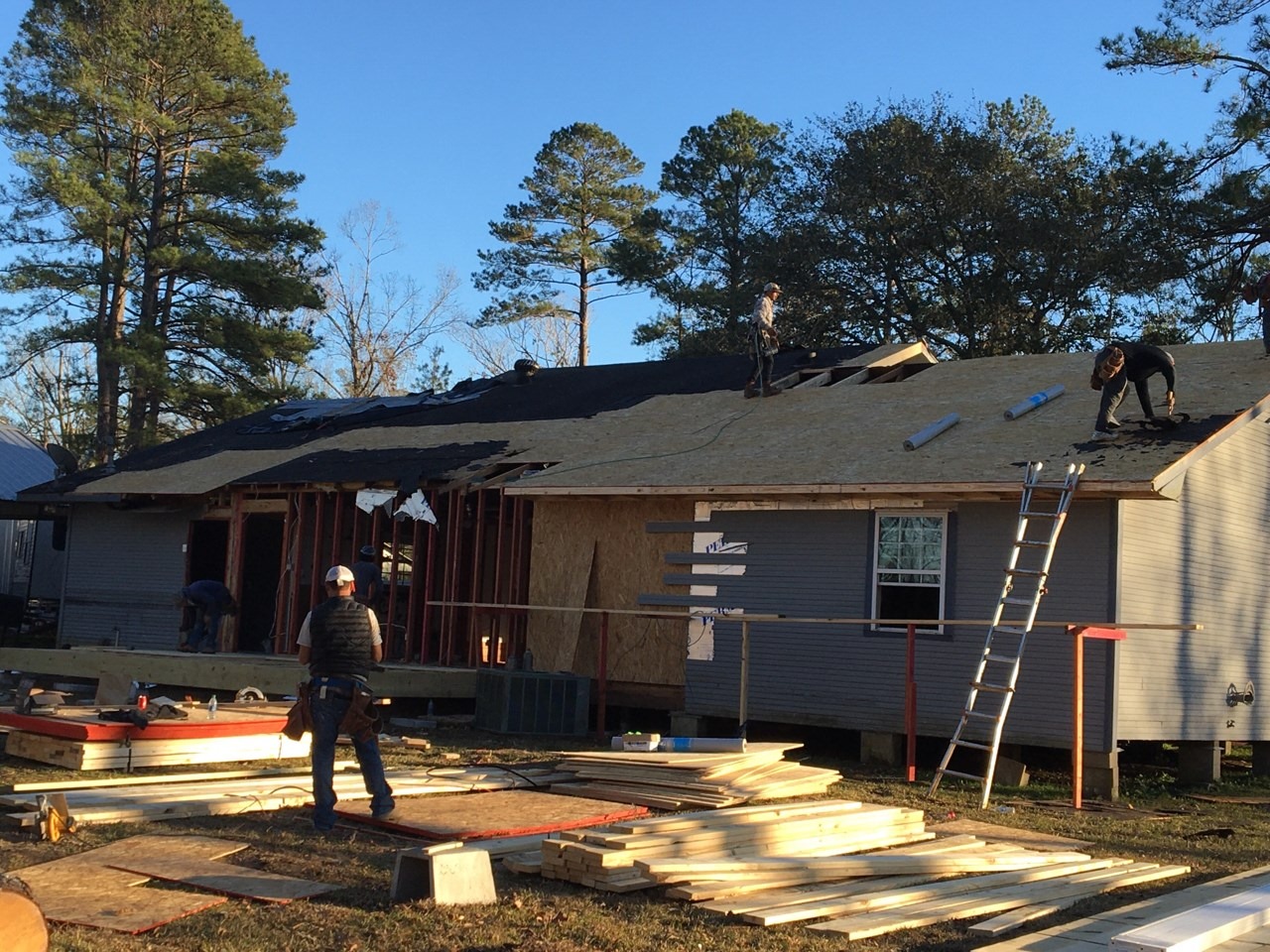 A roofer installing a new roof in progress on a residential home